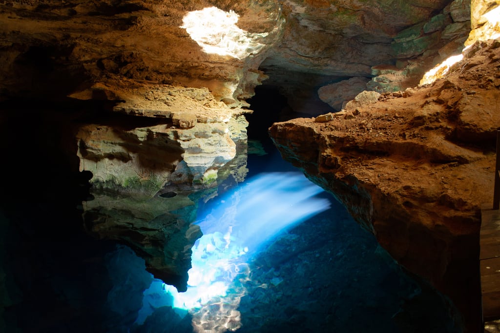 Swimmers floating in the clear blue water of Poço Azul