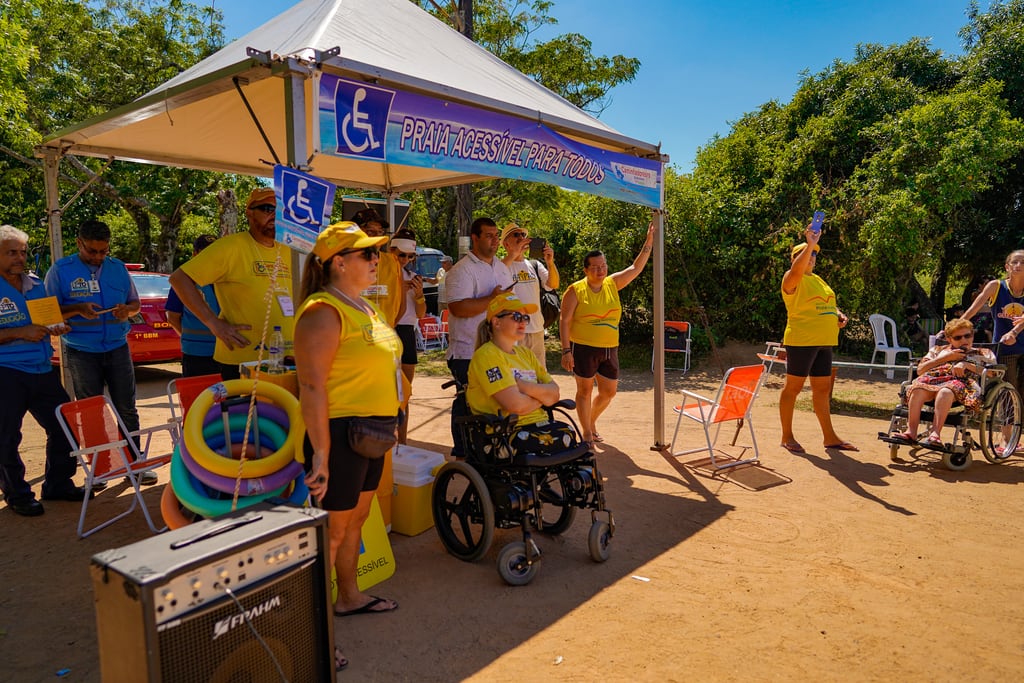 Staff assisting a beach wheelchair user into the water at an adapted beach point